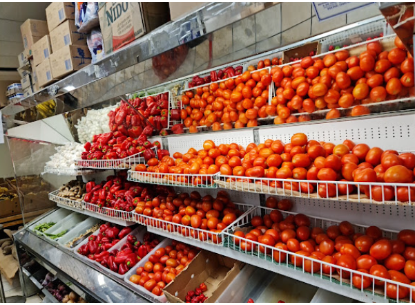 Fresh tomatoes, scotch bonnet peppers and produce on refrigerated shelves